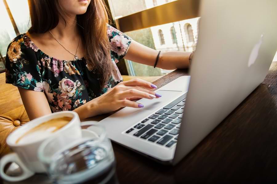 Una lavoratrice nel suo ufficio al portatile, un caffè sulla scrivania | Qipo