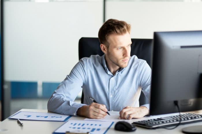 Un lavoratore in ufficio monitora e analizza i dati al computer | Qipo
